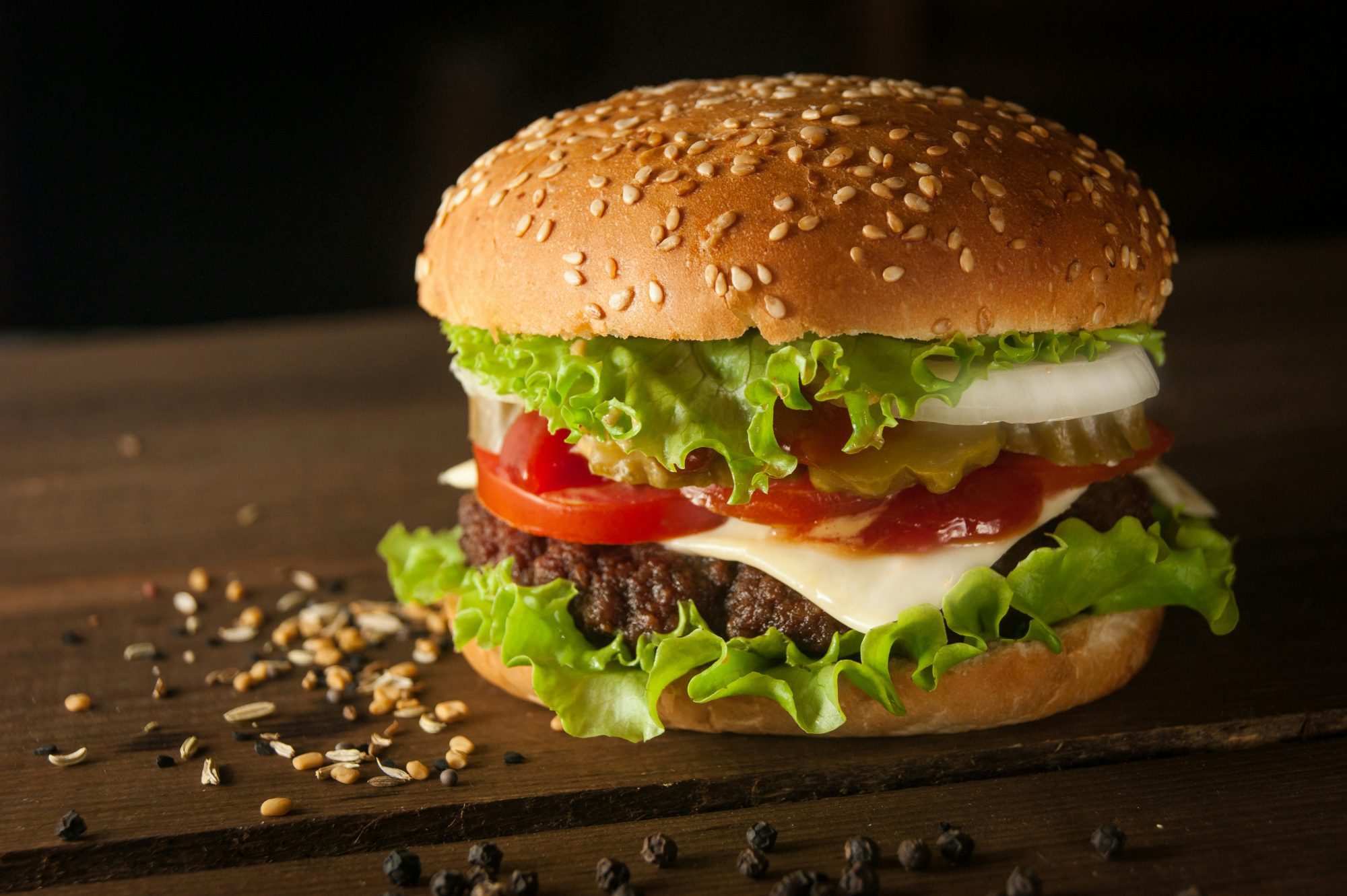 Cheeseburger with a sesame bun sitting on a table.